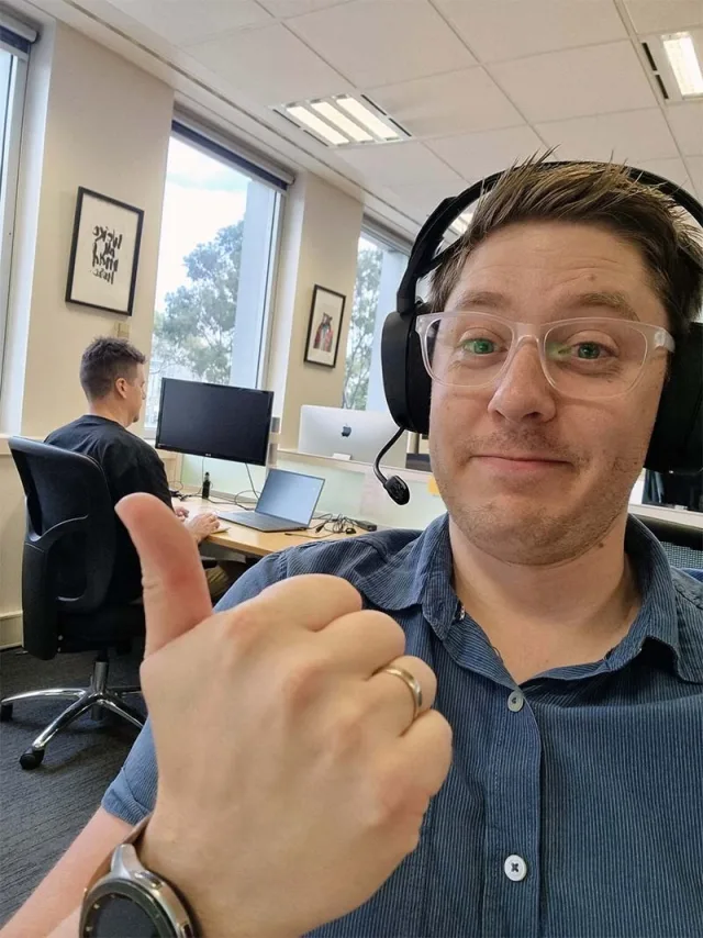 Anthony at his desk with a thumbs up, and Dave working behind him